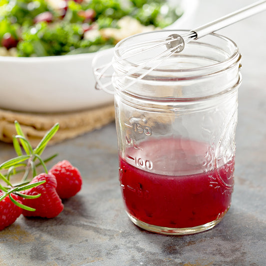 A jar of salad dressing made with summery berry jam